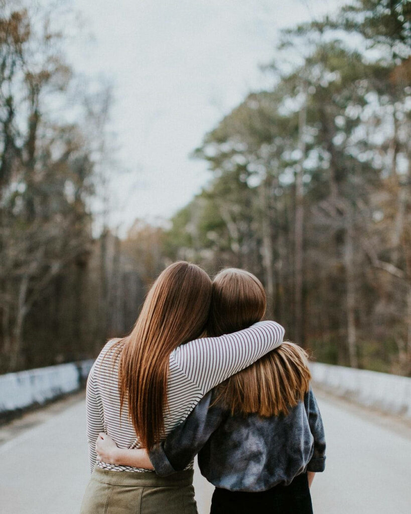 Brunette BFFs Embracing the Serenity of Nature's Highway Wallpaper