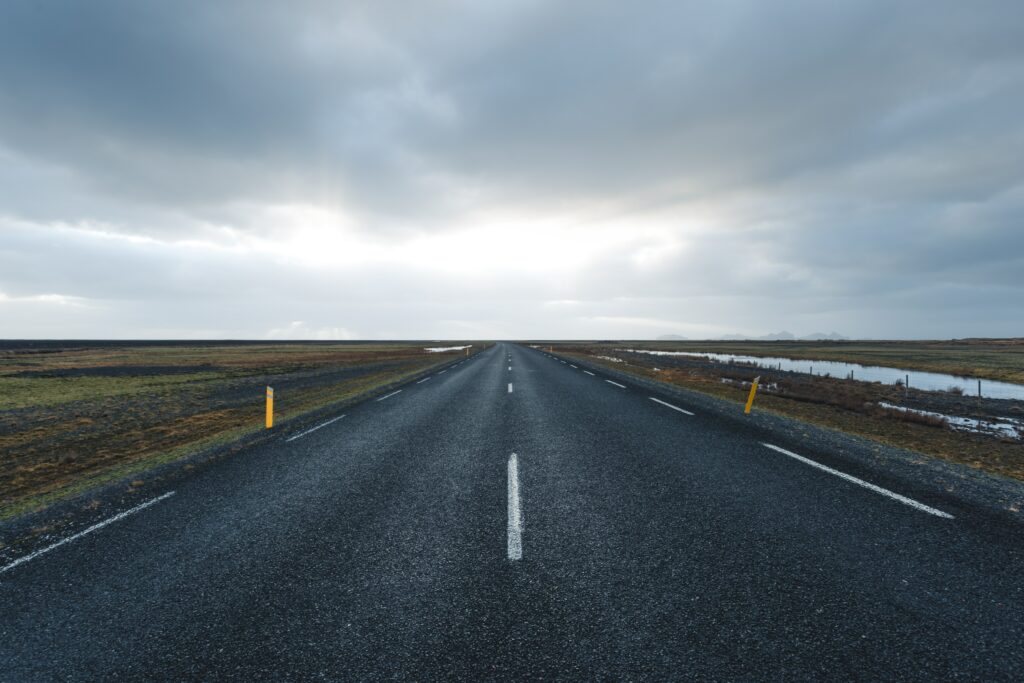 Empty straight road under dramatic overcast sky with blue gray tones minimalist landscape wallpaper
