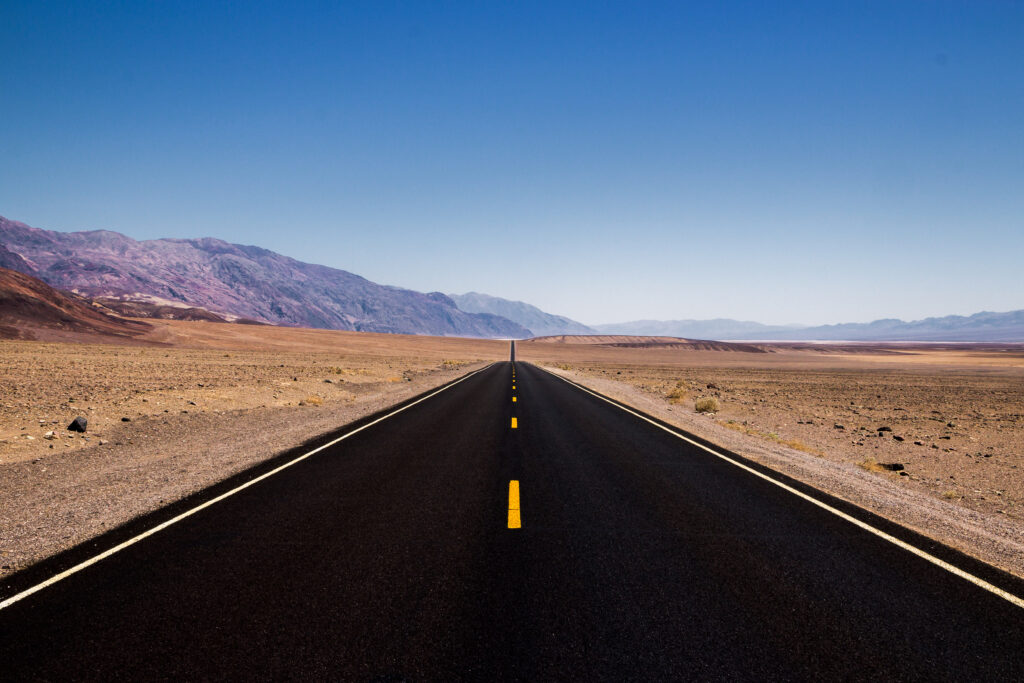 Empty road through rugged hills in vast valley under clear blue sky natural landscape wallpaper