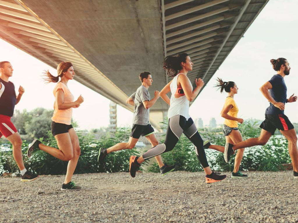 Diverse group jogging on scenic riverside path under bridge vibrant healthy active lifestyle wallpaper