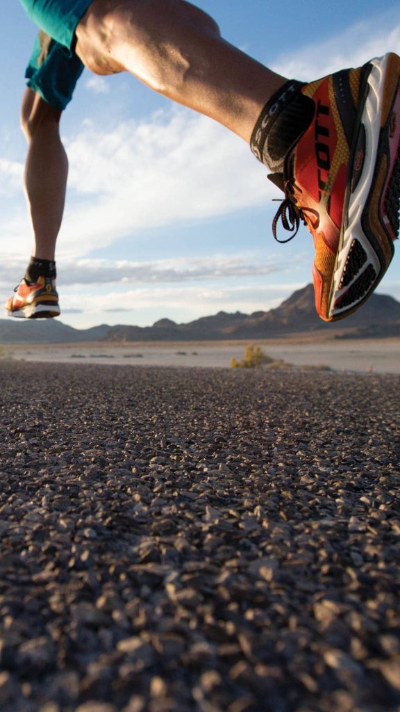 Runner in vibrant Scott shoes mid-stride against desert mountain backdrop energizing jog wallpaper
