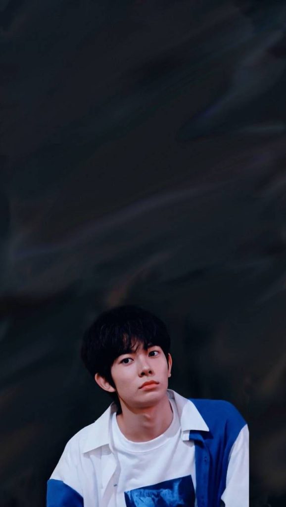 Enhypen Heeseung wallpaper portrait in white blue top on dark moody abstract background mobile