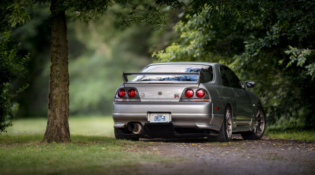 Captivating Capture: Nissan Skyline Gtr R33 Commands Attention near Enchanting Tree Wallpaper