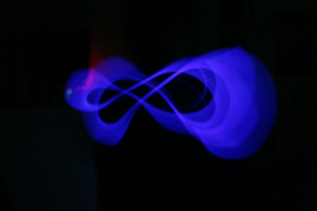 Ethereal Glowing Blue Infinity Symbol on a Vibrant Blackscape Wallpaper