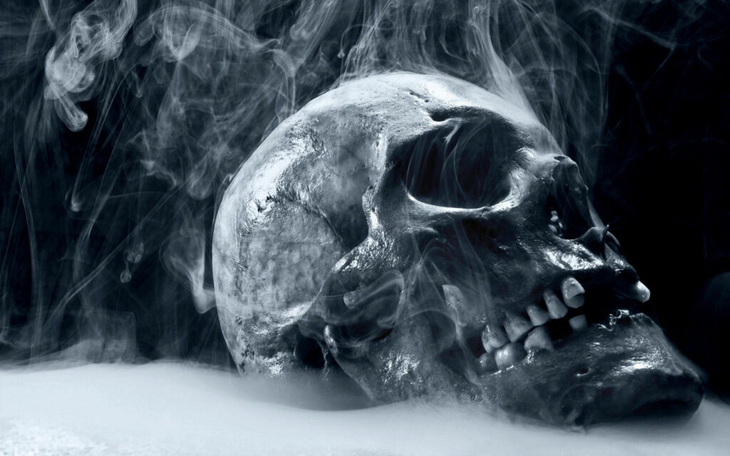 Phantasmal Atmosphere: Eerie Halloween Snapshot featuring a Smokey Mist Enveloping a Sinister Black Skull Wallpaper