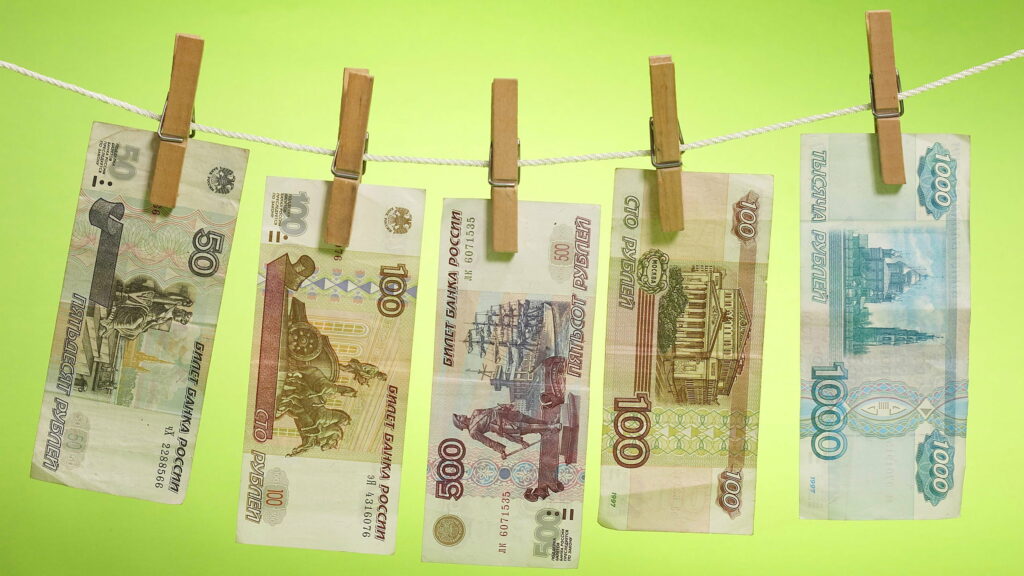 Money on Display: Hanging Currencies Against a Vibrant Green Backdrop - QHD Wallpaper