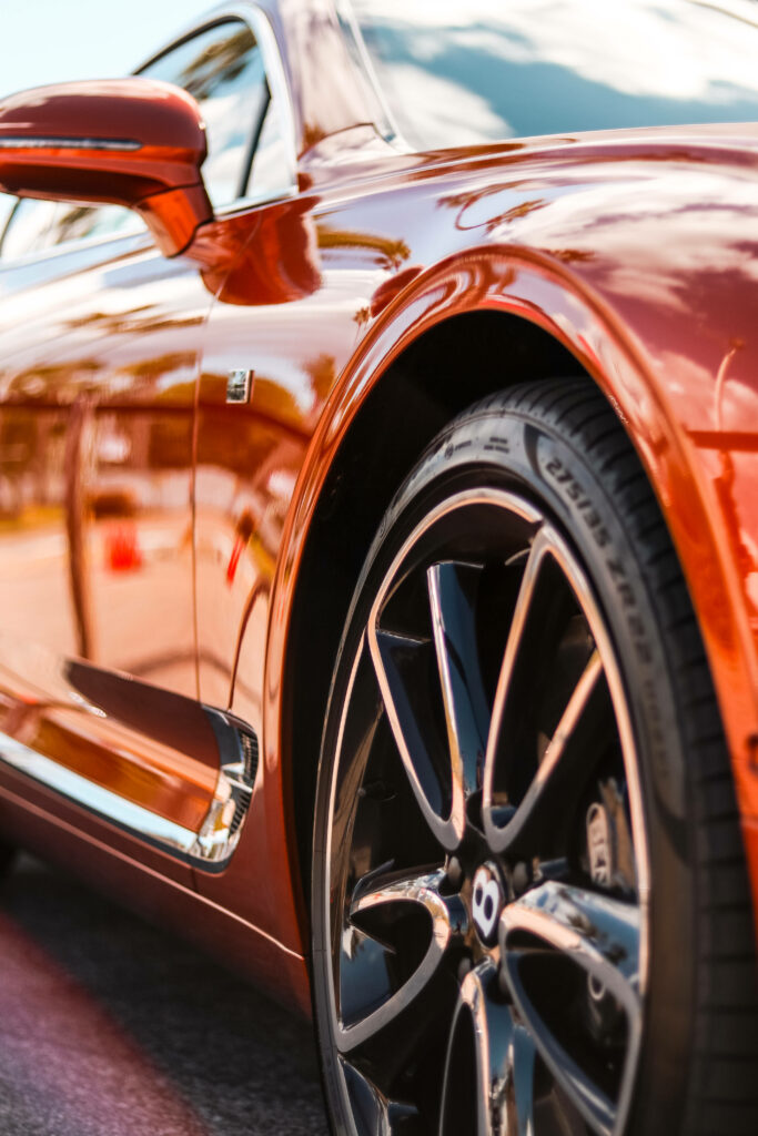 The Alluring Orange Bentley: A Captivating Close-Up of the Wheel with the Iconic B Logo Wallpaper