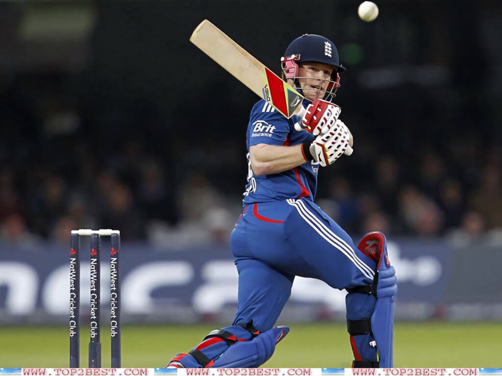 Eoin Morgan playing cricket shot in England kit on green field with focused expression wallpaper background