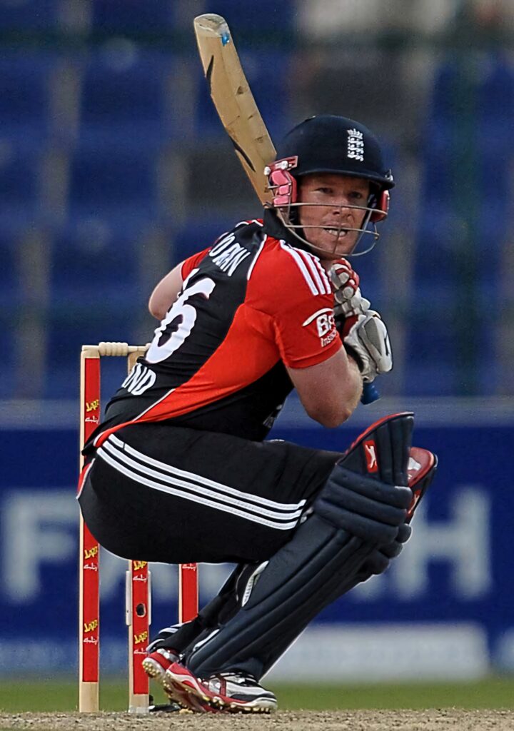 Eoin Morgan batting in England cricket kit with intense focus in vibrant stadium background wallpaper