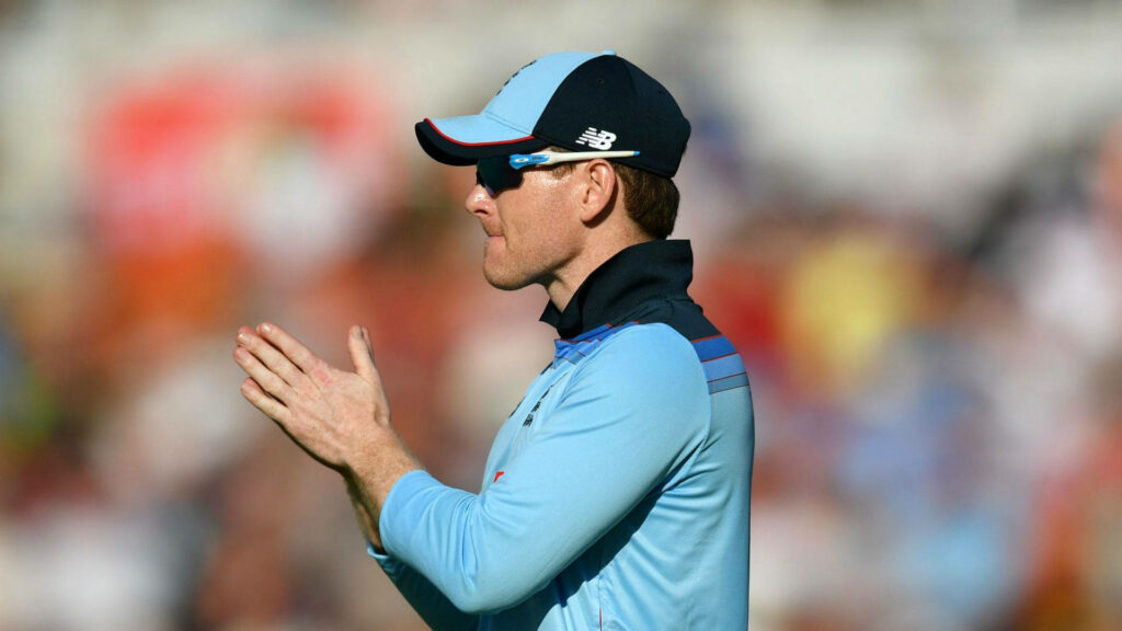 Eoin Morgan clapping in blue England cricket kit with stadium background in dynamic sunlight Wallpaper