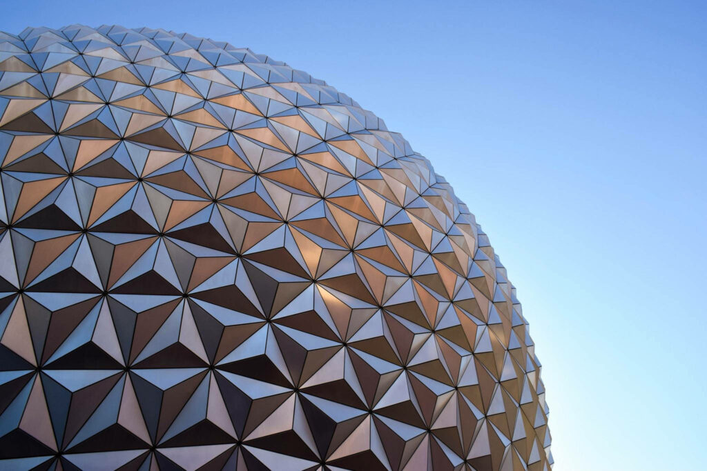 Close-up of Epcot globe with geometric panels and metallic texture against clear blue sky wallpaper