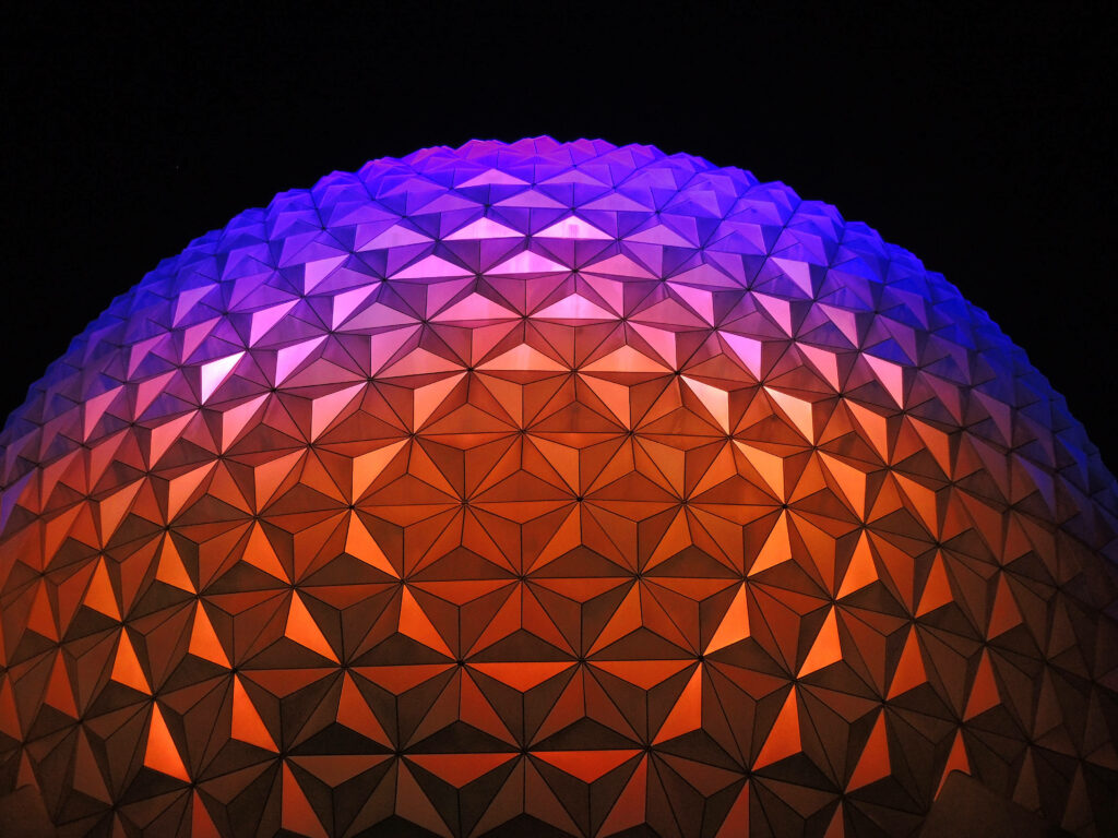Epcot Globe wallpaper illuminated in vibrant orange and purple geometric patterns on black background