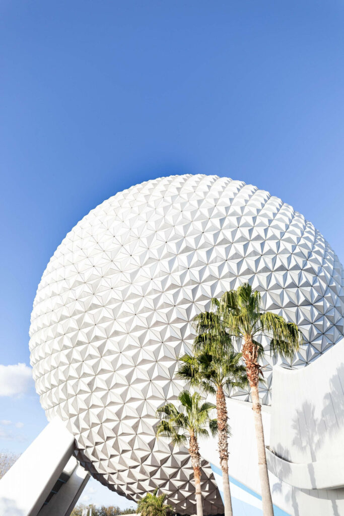 Epcot Globe with geometric panels under blue sky and palm trees Disney travel wallpaper background