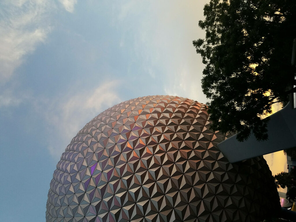 Epcot Globe at sunset with warm orange sky tree silhouette and geometric patterns wallpaper background