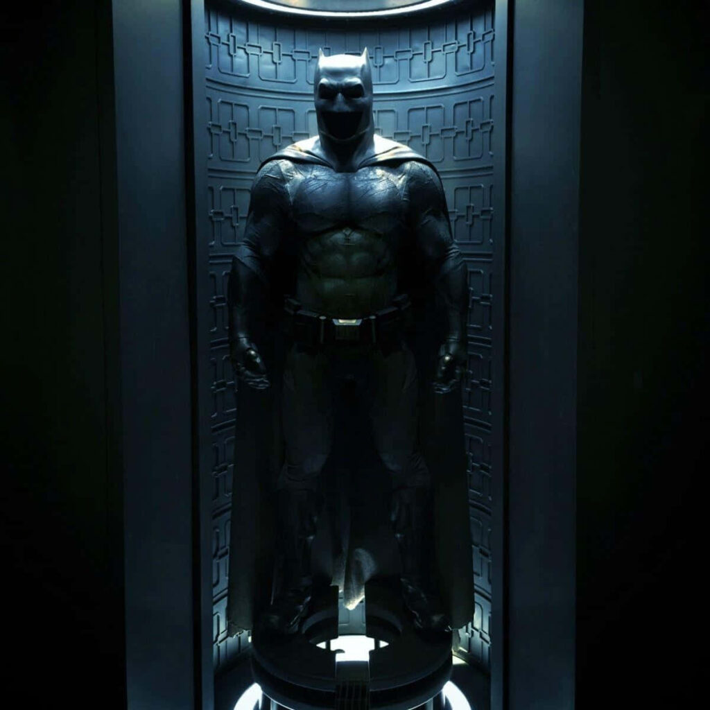 Batsuit in Batcave wallpaper with dramatic lighting showcasing detailed Batman armor background