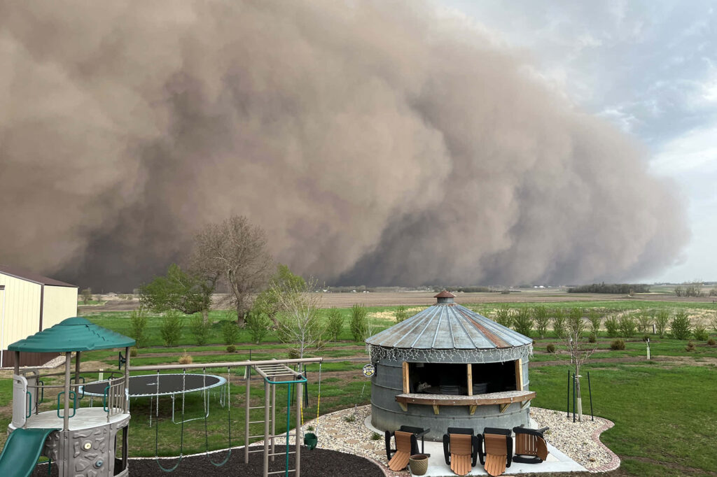 Massive brown dust storm over suburban playground and rustic backyard showing nature's power Wallpaper