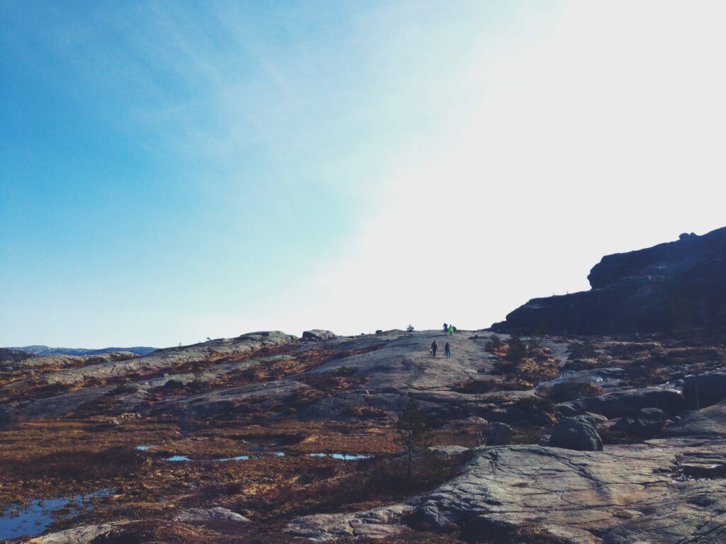 Rugged mountain landscape with climbers trekking rocky terrain under clear blue sky wallpaper