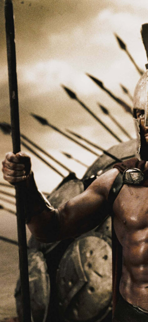 Spartan warrior standing strong on battlefield with arrows flying in dramatic sky background Wallpaper