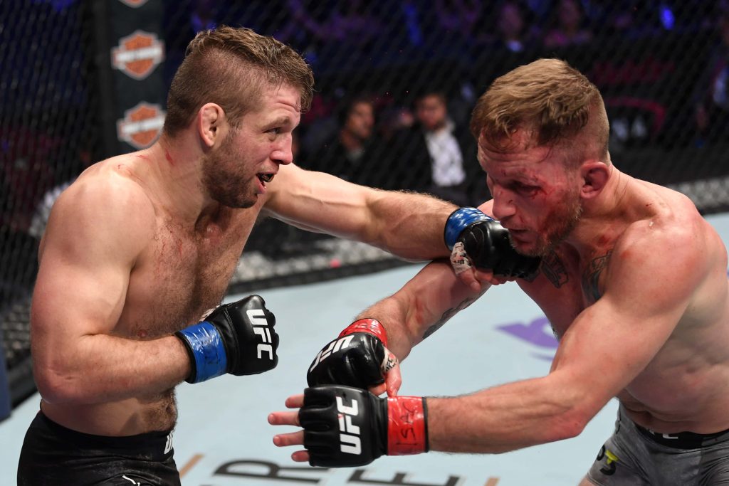 Intense UFC fight Cody Garbrandt vs TJ Dillashaw bloodied trading strikes in octagon cage arena Wallpaper