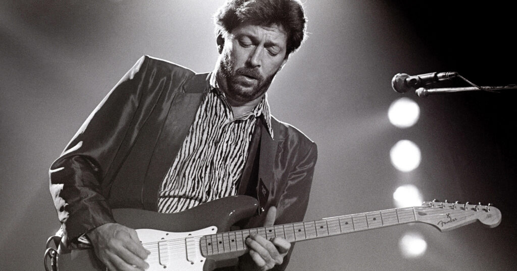 Eric Clapton passionately plays guitar on stage black and white wallpaper showcasing legend skills