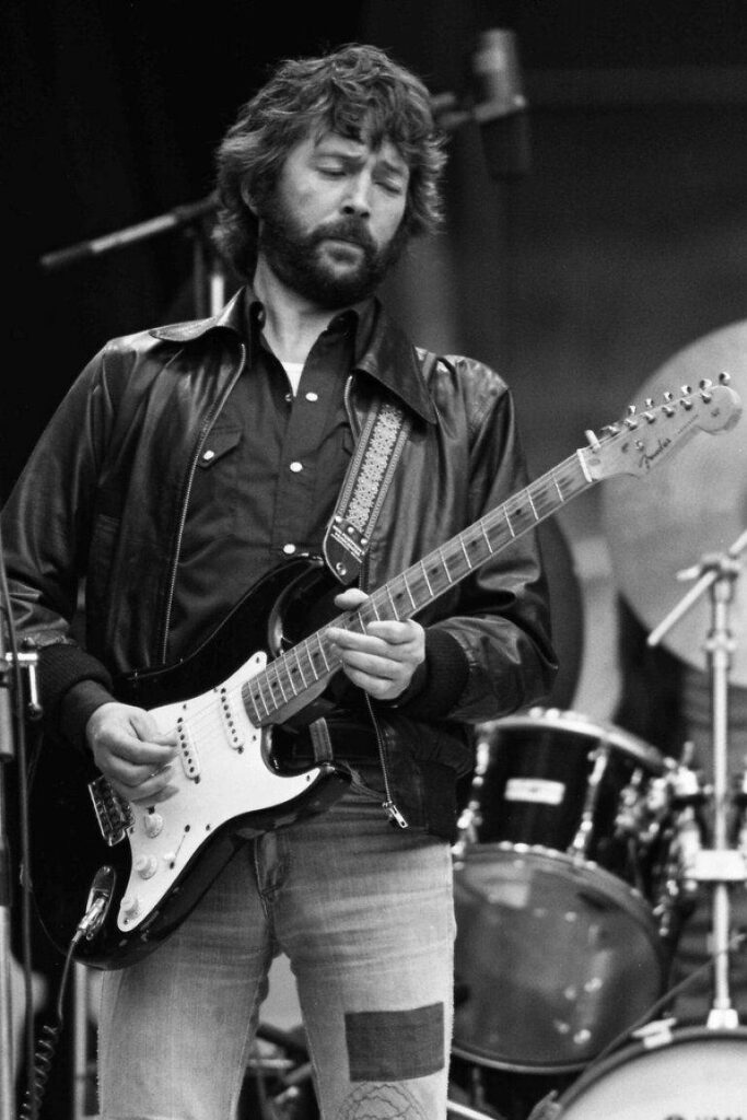 Eric Clapton playing electric guitar on stage classic rock leather jacket jeans wallpaper background