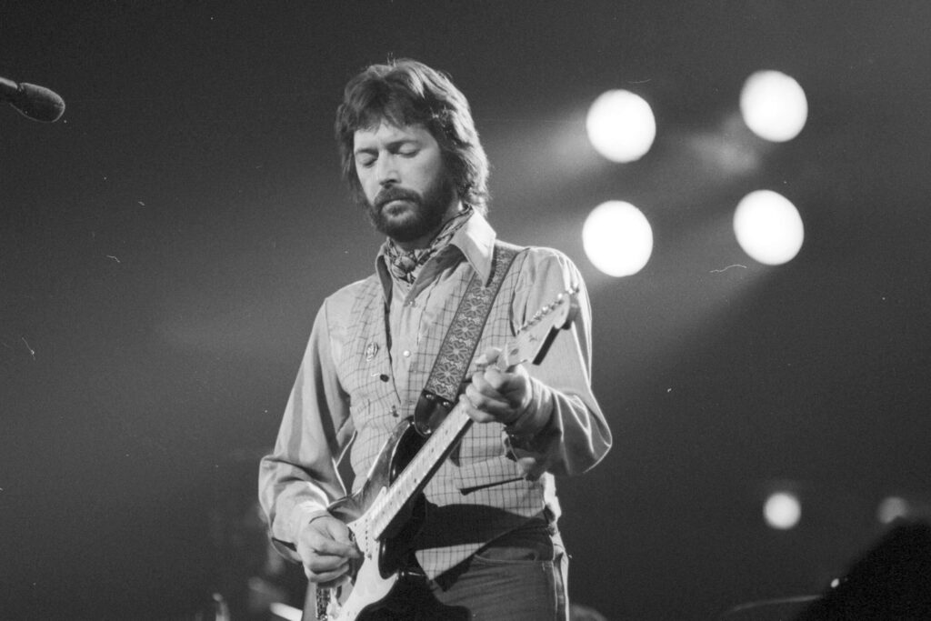 Eric Clapton playing guitar on stage with dramatic lighting classic rock concert atmosphere wallpaper