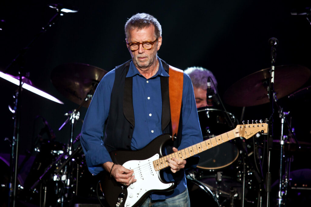Eric Clapton performing live on stage with electric guitar under dramatic concert lighting Wallpaper