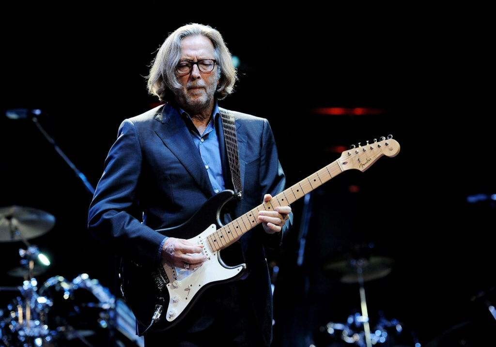 Eric Clapton playing electric guitar on stage in later years with dramatic lighting wallpaper