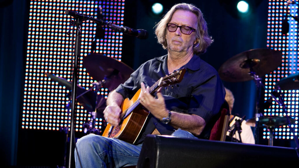 Eric Clapton playing classic guitar on stage vibrant concert lights iconic live music wallpaper