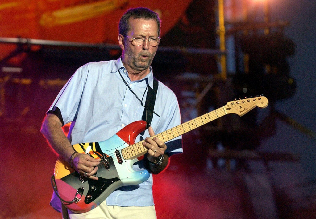 Eric Clapton playing vibrant colorful guitar on stage capturing rock music energy wallpaper background