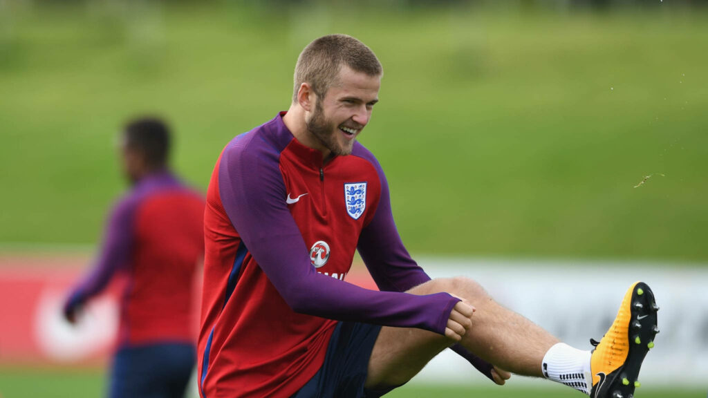 Eric Dier stretching leg in England football kit on vibrant green field training session wallpaper