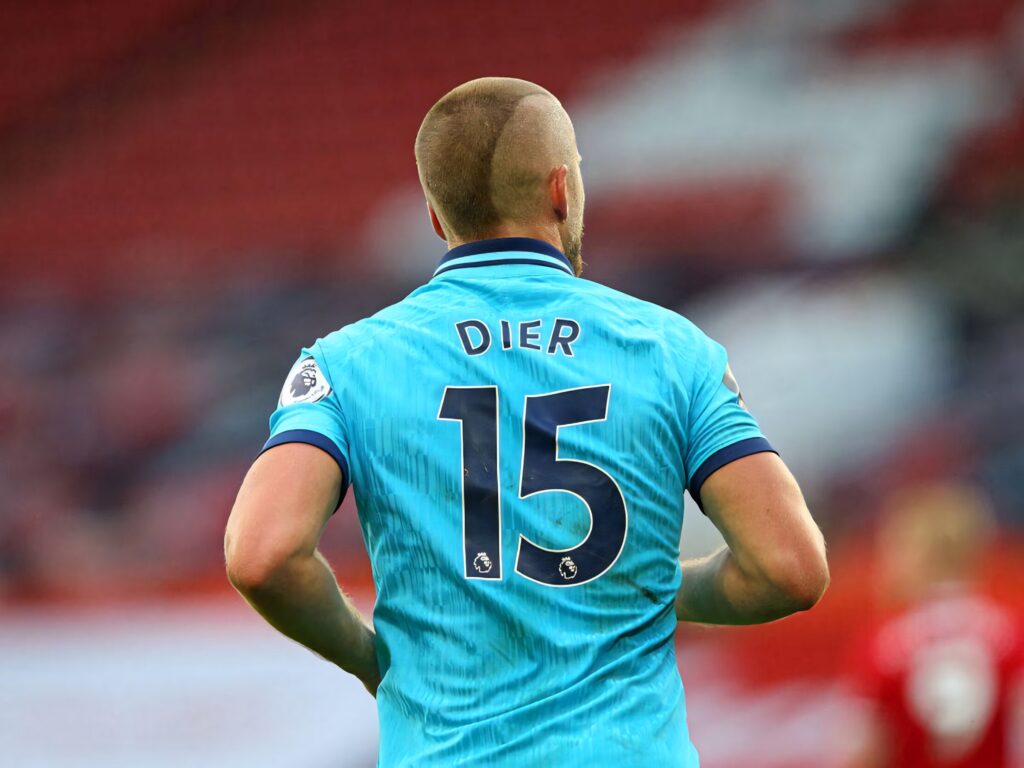 Eric Dier wearing number 15 blue football kit on pitch with blurred stadium background wallpaper