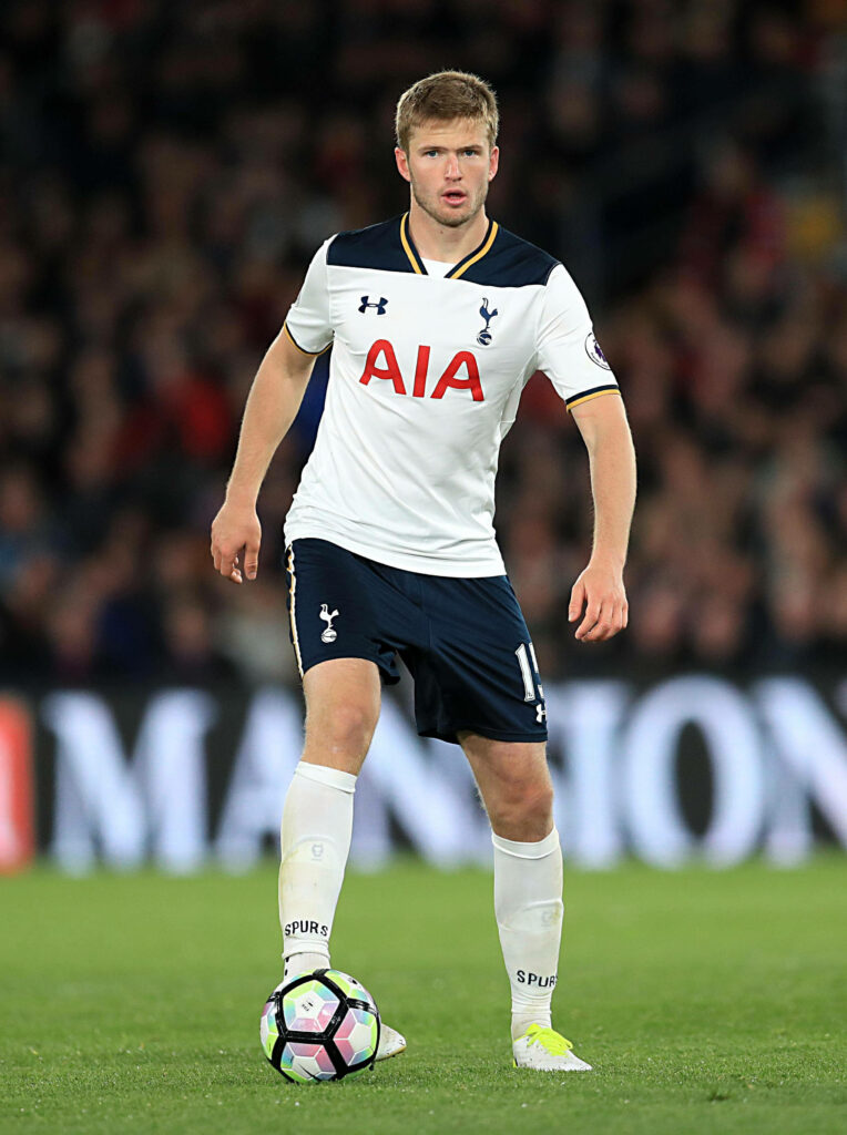 Eric Dier in Tottenham Hotspur kit poised on football field with vibrant stadium lights background Wallpaper