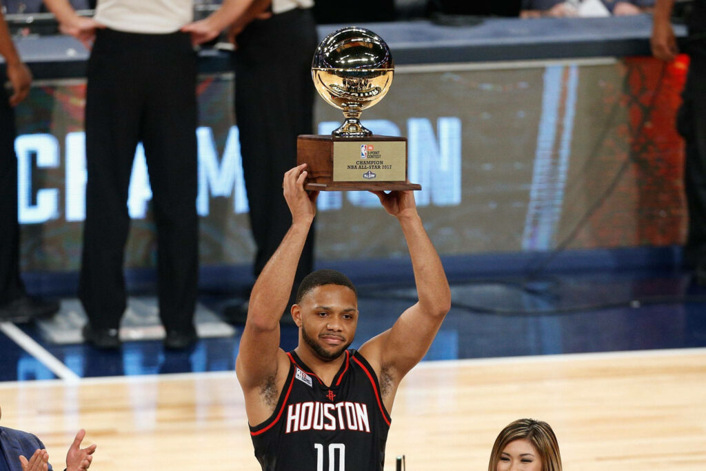 Eric Gordon lifts NBA 3-Point Contest trophy wearing Houston Rockets jersey in vibrant arena Wallpaper