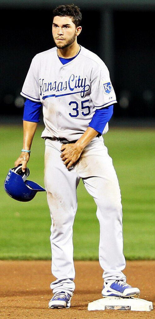 Eric Hosmer in dirty Kansas City Royals uniform holding cap on vibrant green baseball field Wallpaper
