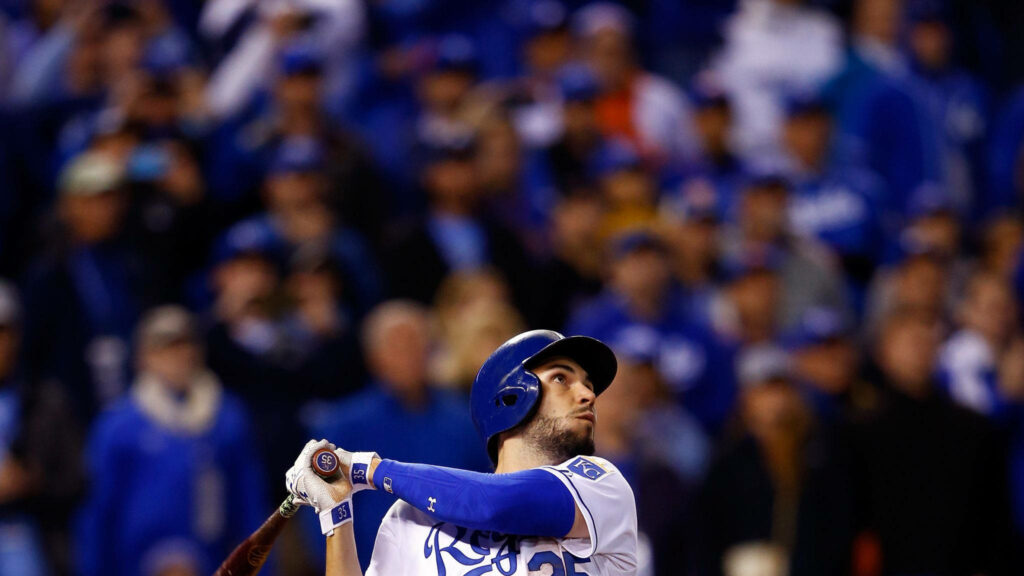 Eric Hosmer mid-swing in Kansas City Royals jersey vibrant stadium background baseball action Wallpaper
