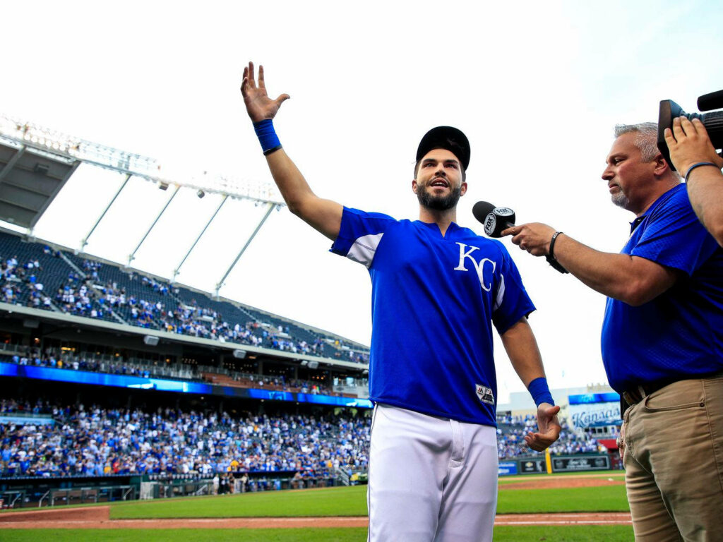 Eric Hosmer mid-interview in Kansas City Royals jersey with lively crowd and bright stadium light Wallpaper