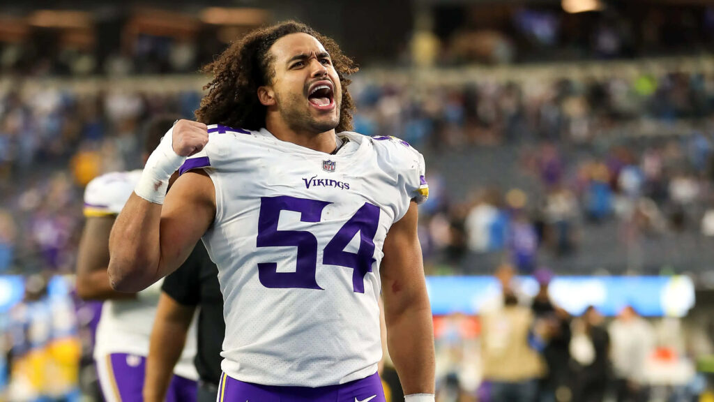 Eric Kendricks in purple Vikings uniform celebrating passionately on football field with blurred stadium background Wallpaper