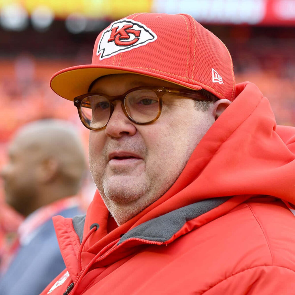 Eric Stonestreet in Kansas City Chiefs cap and red jacket at vibrant stadium showing fan spirit Wallpaper