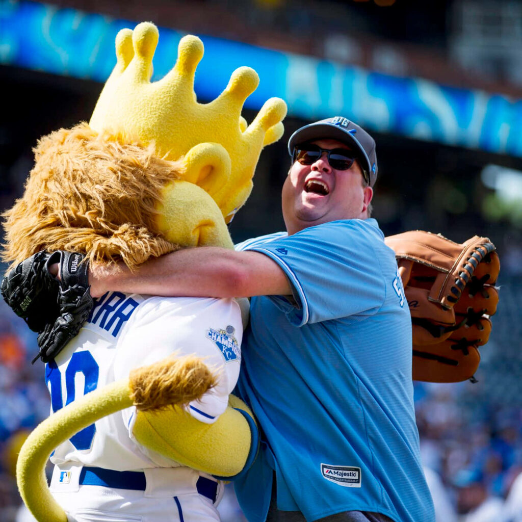 Eric Stonestreet hugging Kansas City Royals mascot Sluggerrr at Big Slick Celebrity Softball Game Wallpaper
