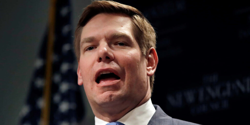 Eric Swalwell speaking with blurred American flag background professional leadership wallpaper