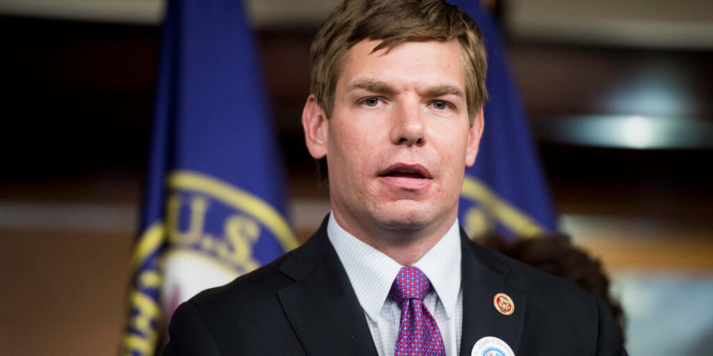 Eric Swalwell portrait in suit with U.S. flags blurred background professional patriotic tones Wallpaper