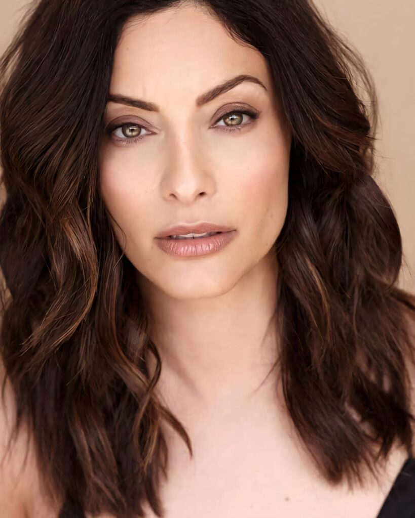 Close-up portrait of Erica Cerra with expressive eyes and soft dark brown waves on beige background Wallpaper