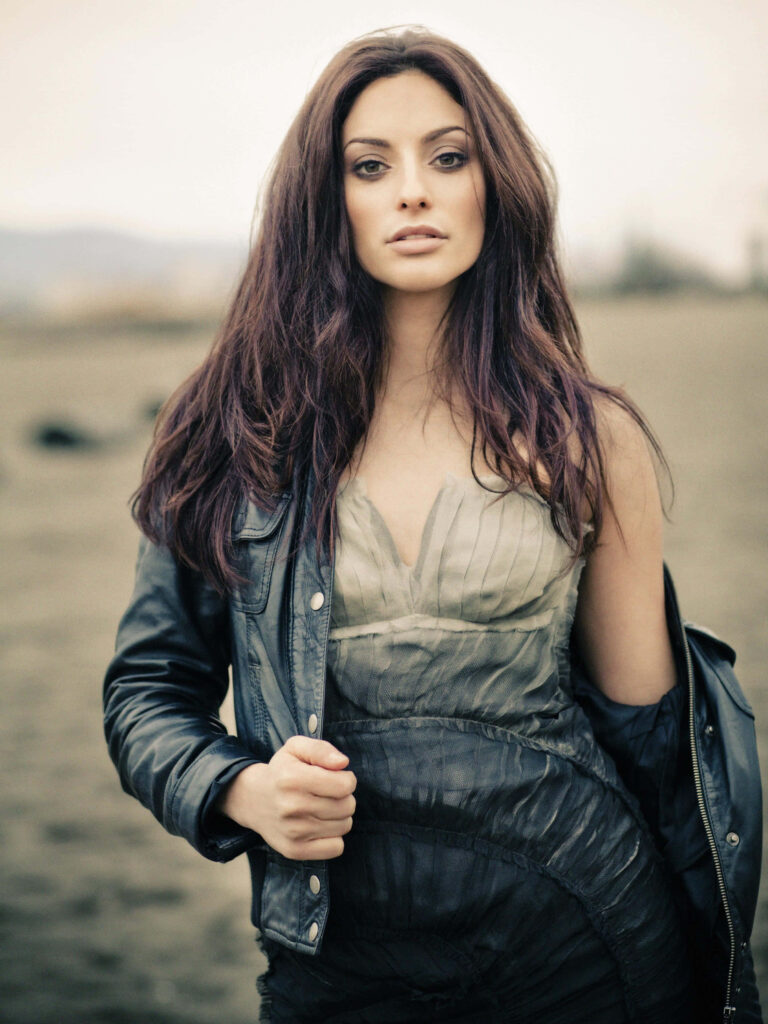 Erica Cerra confident portrait wearing dark jacket and textured dress with soft natural lighting Wallpaper