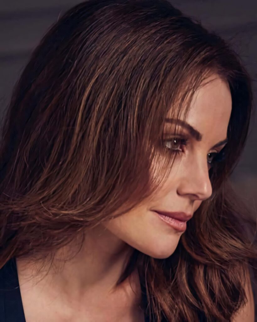 Close-up portrait of Erica Durance with brown hair and natural makeup on muted modern background Wallpaper