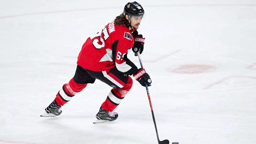 Erik Karlsson in Ottawa Senators jersey skating intensely with hockey stick on ice rink Wallpaper
