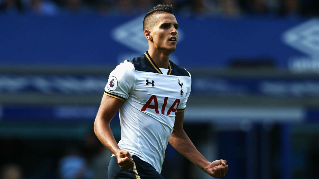 Érik Lamela in Tottenham Hotspur kit showing determination on deep blue football pitch wallpaper