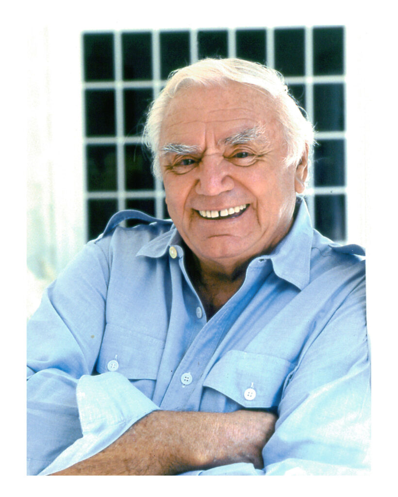 Ernest Borgnine smiling in light blue shirt with warm light and grid window background wallpaper