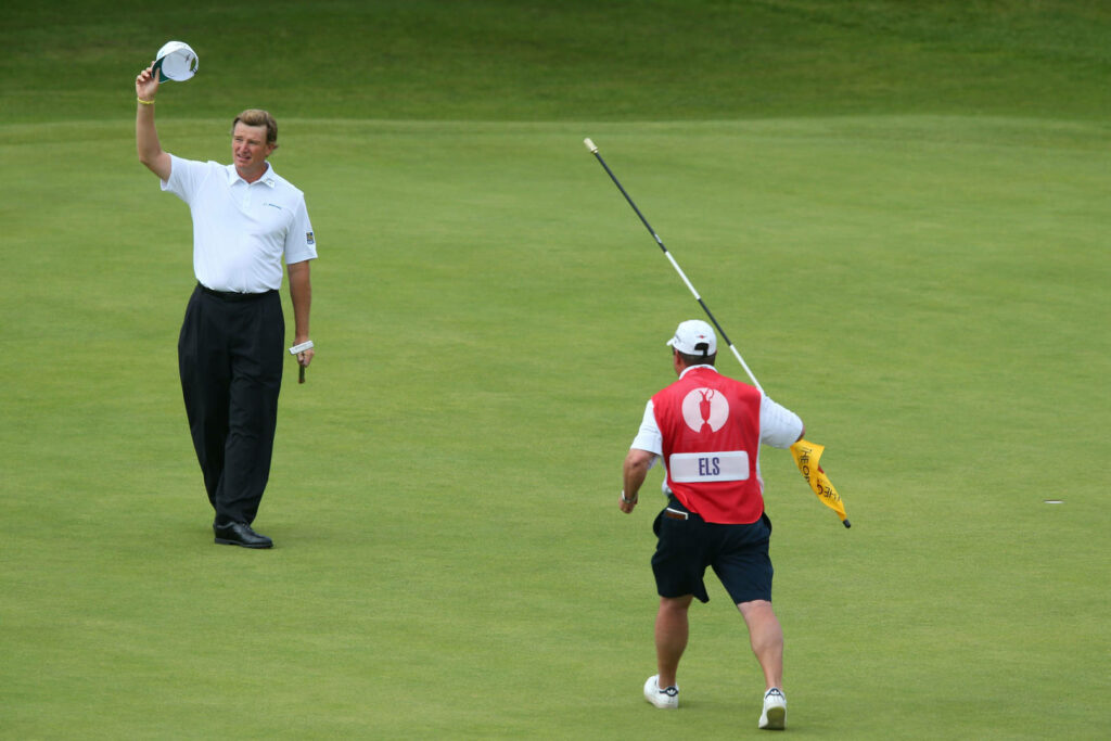 Ernie Els celebrating on green golf course with caddy carrying flagstick during pro tournament Wallpaper