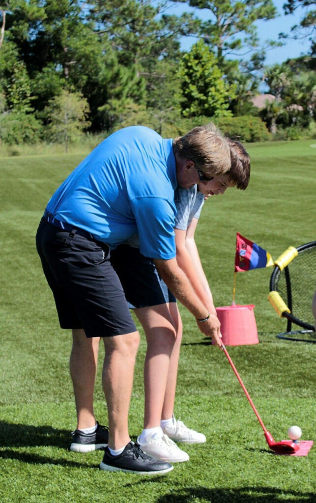 Ernie Els coaching child golf swing on green course bright blue sky mentorship sports wallpaper
